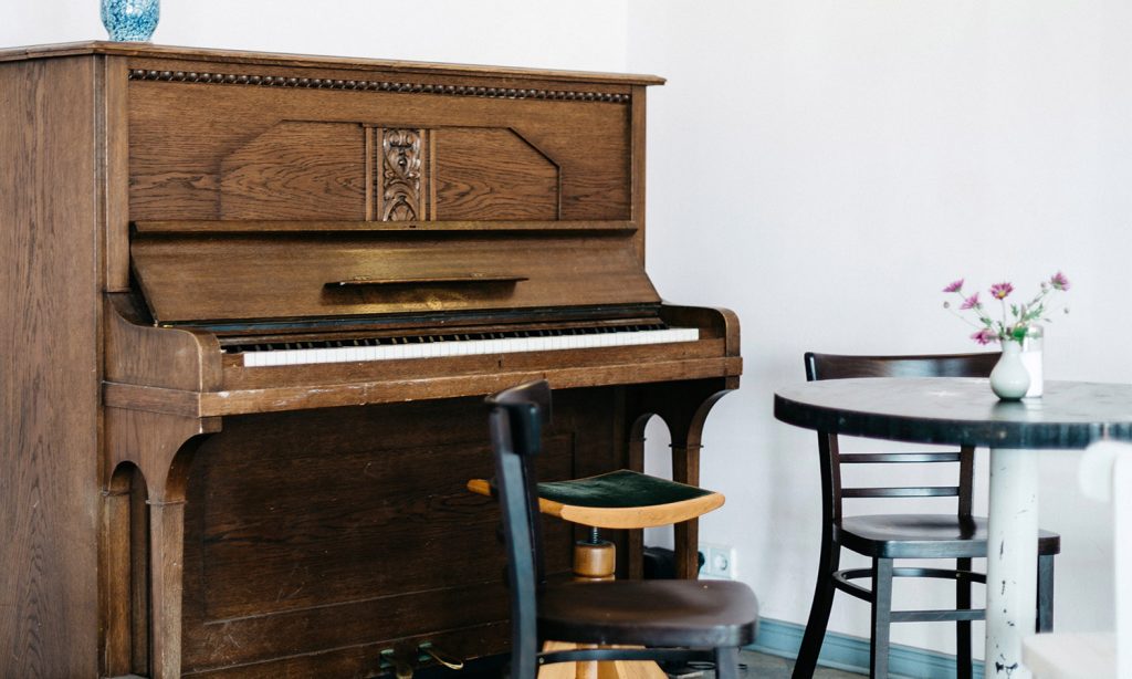 vertical piano in a light room with a few chairs in front of it